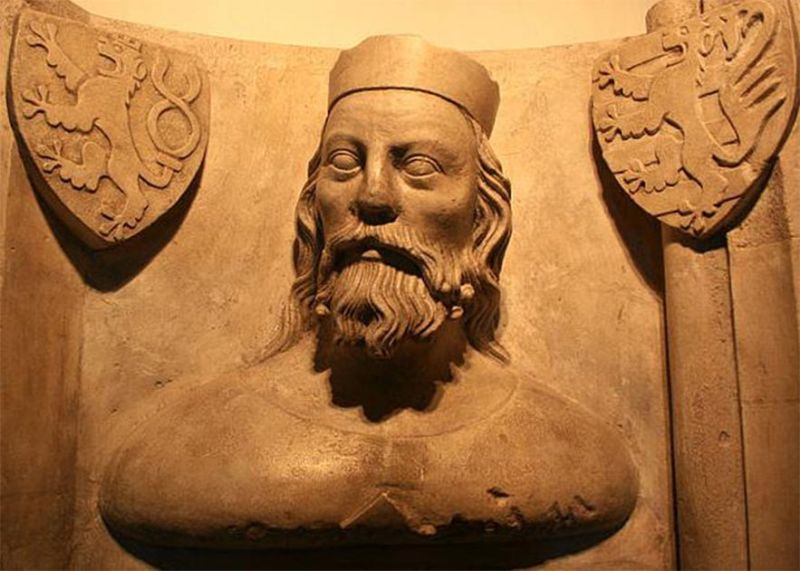 L escultura de un hombre con pelo largo y dos logos a sus lados