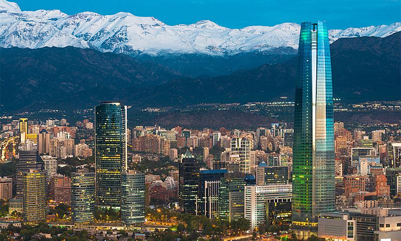 Vemos a una hermosa grande ciudad con rascacielos y edificios avenidas y rodeada de montañas