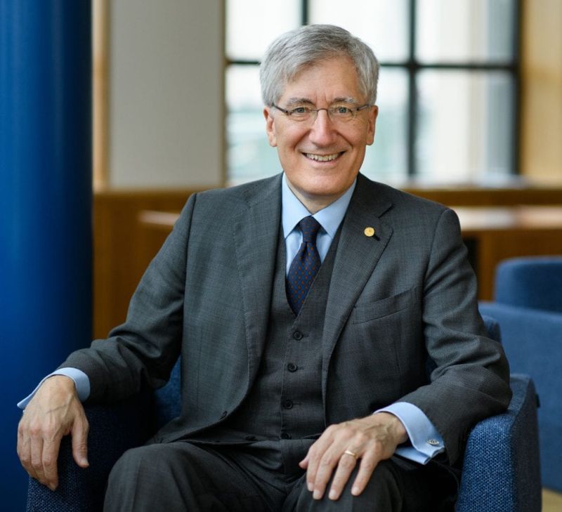 Hombre sonriente que lleva traje y corbata mientras está sentado