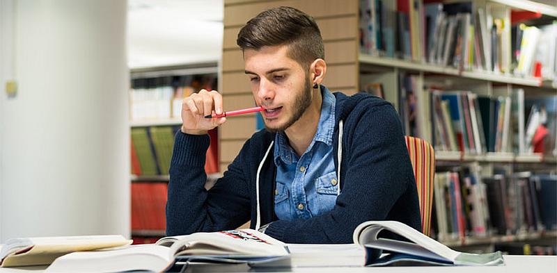 Vemos aun hombre joven en una biblioteca estudiando