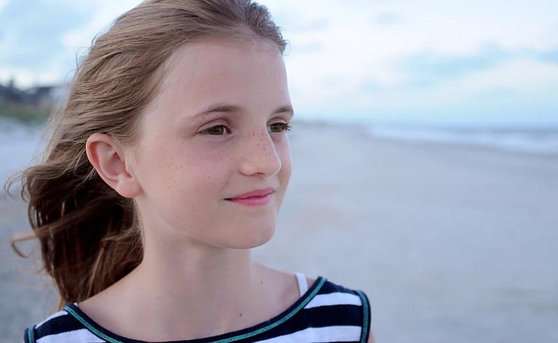 Vemos a una adolescente que mira el paisaje y sonrie