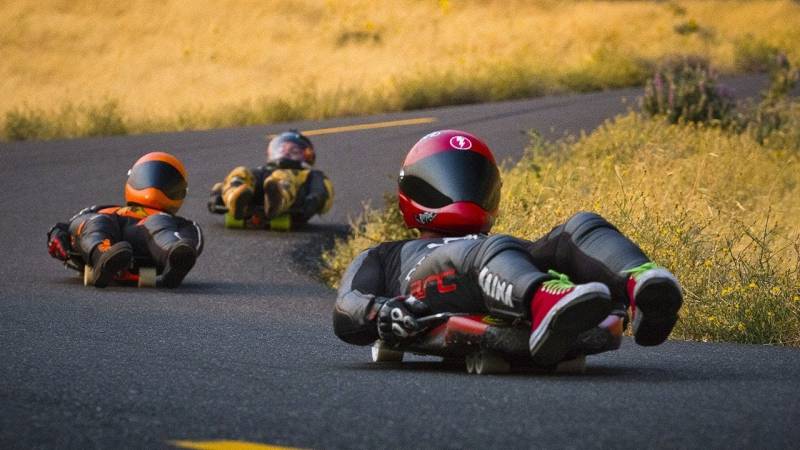 Varias personas en sus trineos con equipos de protección puestos tomando una curva