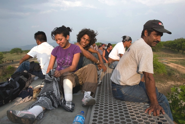 Varias personas sobre el vagón de un tren nada cómodo sonríen tranquilamente