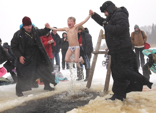 Vemos aun pequeño niño que lo van a sumerguir dos monjes en una agua congelada en  un rito religioso