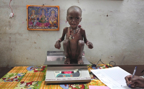 Una pequeña niña subida en una pesa muestra la cantidad de peso que tienee