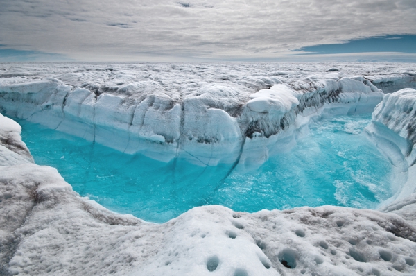 UN glacial enorme donde se ven pequeñas partes descongeladas por donde corre agua muy transparente