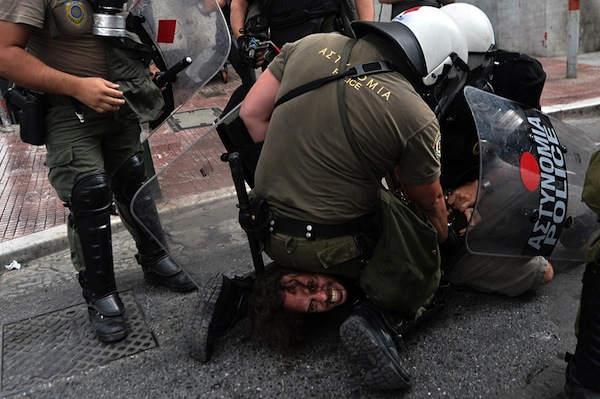 Unos policias detienen a un hombre durante una manisfestacion y lo llevan al suelo en posicion indefensa