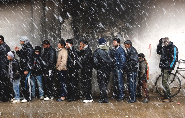 tenemos una fila de hombres solos que esperan por comprar algo se ve que llueve intensamente