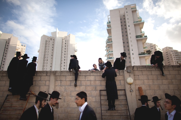 Vemos a los judios ultra ortodoxos con sus trajes subiendo a un muro y mirando al otro lado a la espera de algo