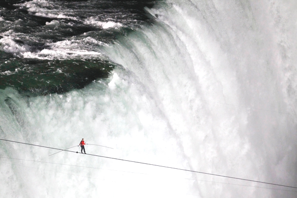 Vemos unas cataratas muy grandes donde un hombre camina sobre un cable para llegar al otro lado