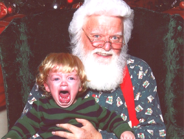 Un niño sentado encima de Santa Claus llora muerto de terror y quiere irse
