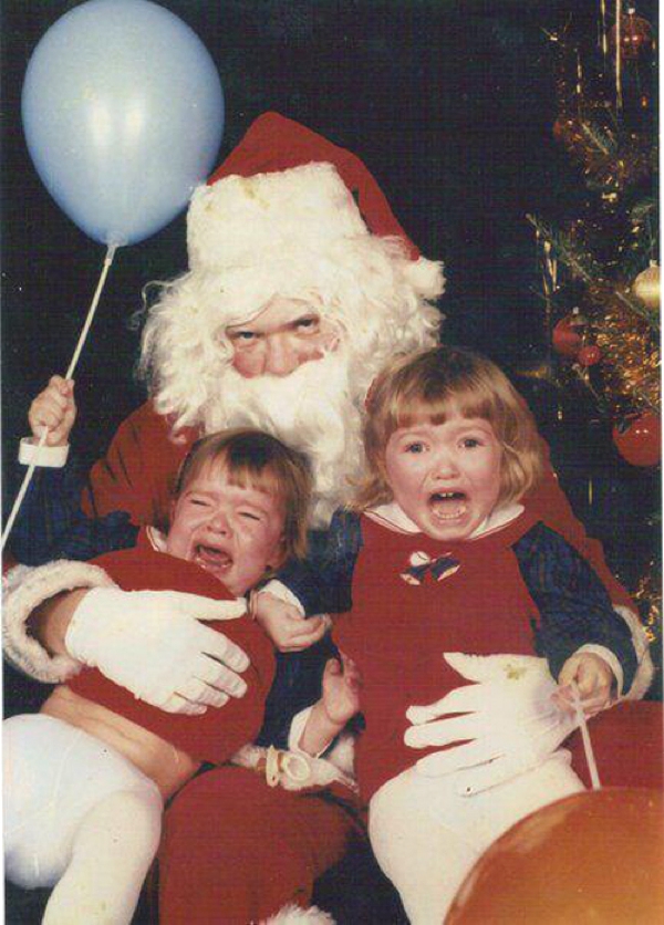 Vemos a Santa Claus con  dos niños sentados en sus piernas lloran sin consuelo  el lleva un globo en su mano de color blanco