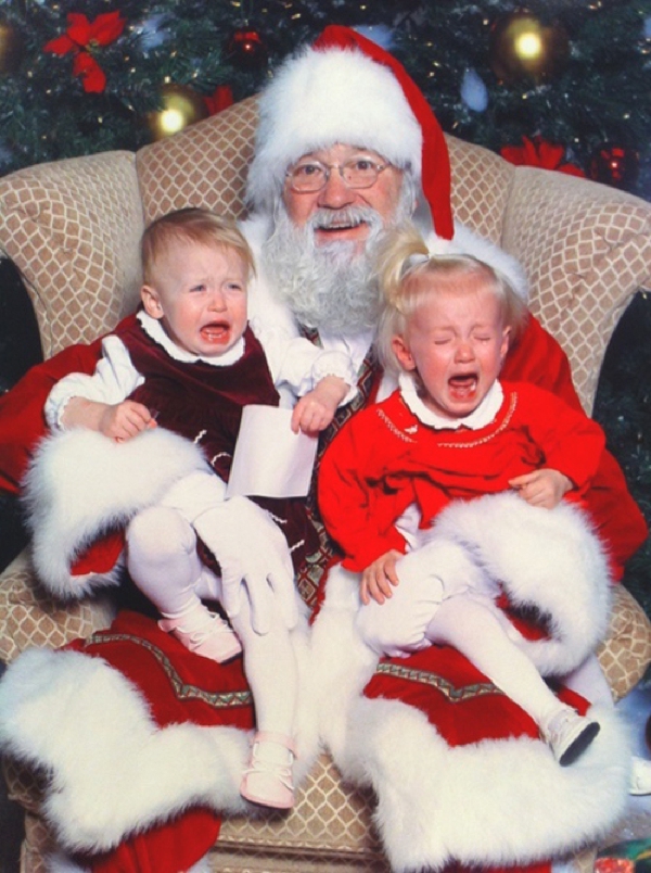 Dos niños niña y niño muy bien vestidos sentados encima de Santa Claus lloran con miedo de El