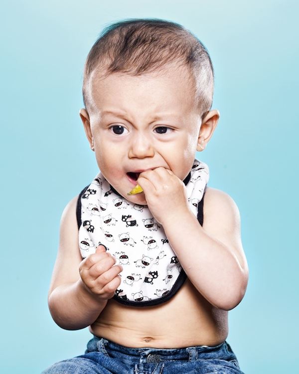 Otro pequeño bebe toma el limón entre sus dientes a un no hace un  gesto de rechazo