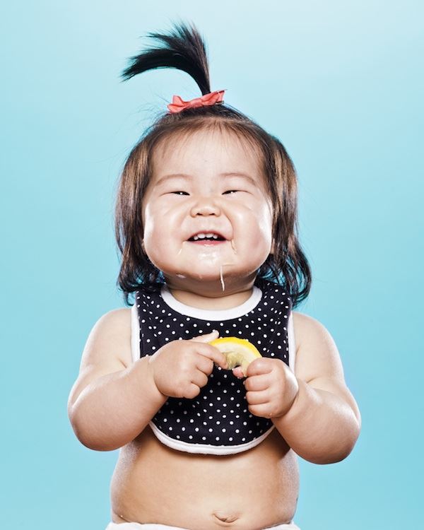 Una pequeña niña oriental disfruta el sabor del limon no tiene rostro de desaprobacion